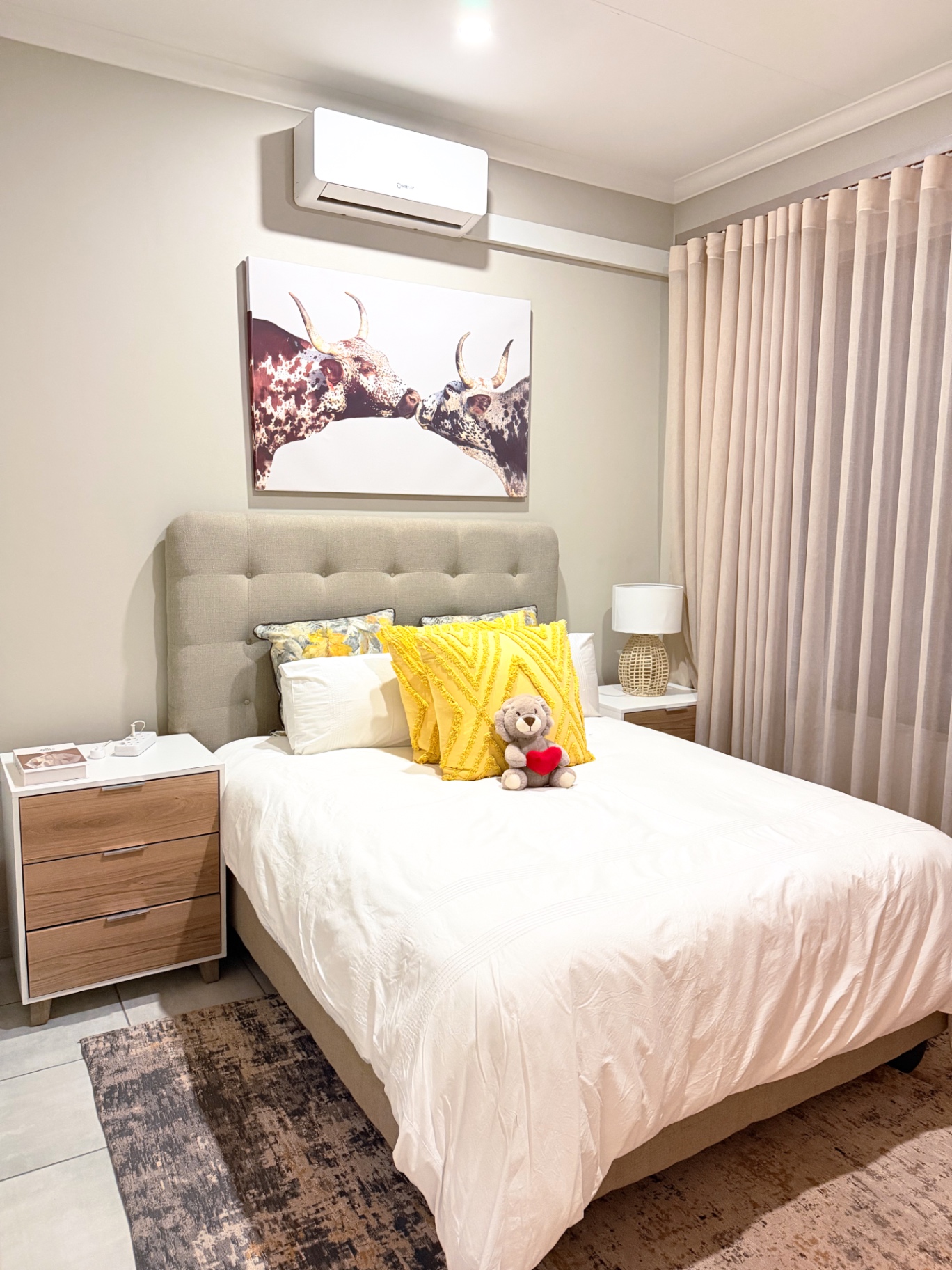 Master bedroom with tufted headboard and Nguni artwork